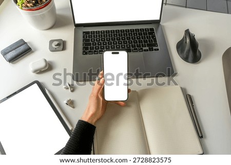 POV creative office mockup with empty smartphone screen for app design. Minimalistic desk, open bullet point notebook, ergonomic mouse, smart ring and digital devices.