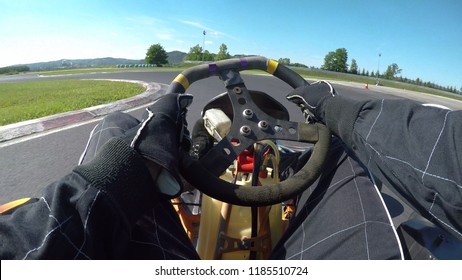 POV: Driving A Fast Go-kart In A Black Suit Through Sharp Bends Of A Bumpy Asphalt Racetrack. Cinematic First Person View Of Steering A Go Cart While Racing In A Fun Competition On The Sunny Circuit.