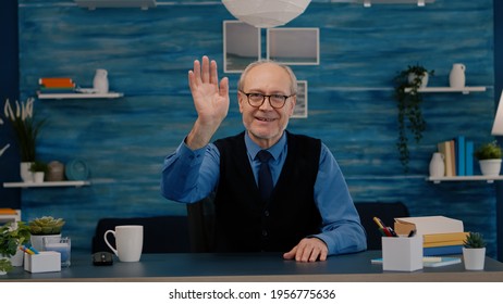 POV Of Elderly Aged Man Waving During A Video Conference With Business Partners Working From Home. Senior Person Using Internet Online Chat Technology Webcam Making Virtual Meeting Call Connection