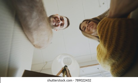 POV Of Happy Couple Kissing While Opening Cardboard Box After Relocation And Looking Inside And Taking Things In New House