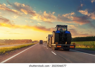 POV Heavy Industrial Truck Semi Trailer Flatbed Platform Transport Two Big Modern Farming Tractor Machine On Common Highway Road At Sunset Sunrise Sky. Agricultural Equipment Transportation Service