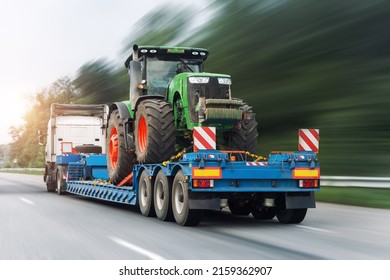 POV Heavy Industrial Truck Semi Trailer Flatbed Platform Transport One Big Modern Farming Tractor Machine On Common Highway Road At Bright Day Sky. Agricultural Equipment Transportation Service Work