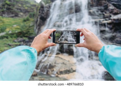 POV Image Of Female Traveler Photographing With Smartphone The Waterfall Outdoor