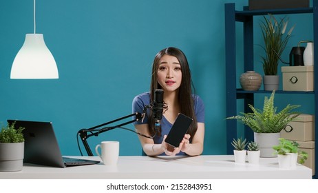 POV Of Influencer Broadcasting Video On Smartphone Review, Filming Vlog On Camera. Female Content Creator Recording Product Recommendation With Moible Phone In Studio. Tripod Shot.