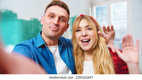 POV Of Joyful Young Caucasian Married Couple Stand In New Apartment During Repair Works Having Conversation On Video Call Online Waving Hands, Home Renovation, Close Up Concept, House Improvement