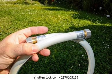 POV Male Hand Holding New Gas Hose In Green Garden Background