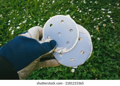 POV Male Hand Holding Used Sanding Paper With Blue Surface In Green Background