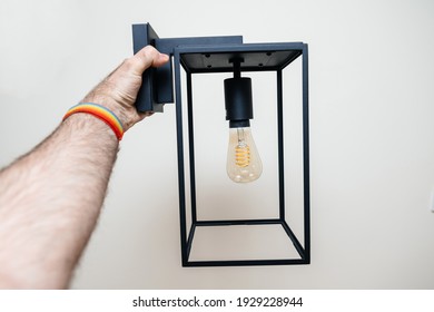 POV Male Hand Looking At Vintage Filament Light Bulb On Box Lantern Wall Light Vintage Style With Edison Filament Bulb After Unboxing Before Installation Isolated On White Background