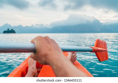 POV Of Man Floating In Kayak Holding  Paddle During Early Morning Tour. Khao Sok National Park, Cheow Lan Lake, Thailand 
