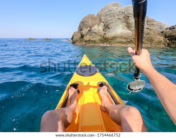 POV of Man floating in a Yellow kayak holding
paddle in Mediteraneean Sea. Point of view shot from inside kayak
on water. Kayaking in Greece.
