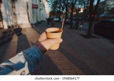 POV man holding cup with takeaway tea and lemon slice at the morning city