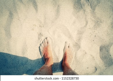 POV of a naked men's feet on the beach, touching the warm sand. Copyspace on the upper part. Mojo colors.
