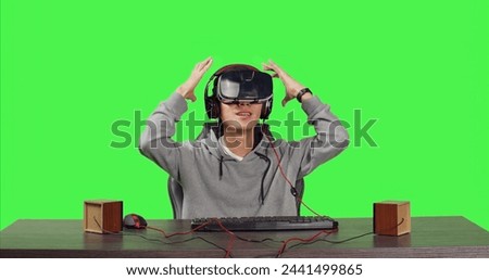 POV of person seated at workstation over full body greenscreen, enjoying virtual reality online games with colleagues. Young adult gaming with vr glasses, playing combat gameplay.
