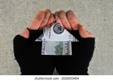 POV (point Of View) Of A Homeless Person Holding A House Made Out From Federal Reserve US Dollar With His Two Hands In City Street. Mortgage Bank Loans Interest Rate And Real Estate Property Concept.