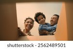 POV point of view open cardboard box looking inside African American happy family joyful parents son kid little boy child unpacking parcel delivery online shop receive package unboxing moving day home