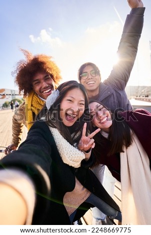 POV selfie of mixed race group of young people looking at camera laughing enjoying their day outdoors at the city. Vertical.