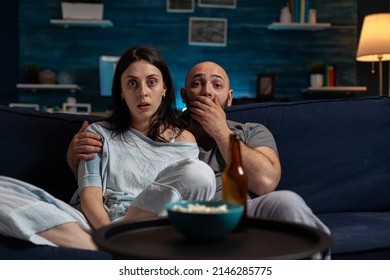 POV Of Shocked Partners Watching Cinema Movie On Television, Feeling Surprised And Doing Wow Expression. Man And Woman With Mouth Open Looking At Scary Film On TV Channel Program.