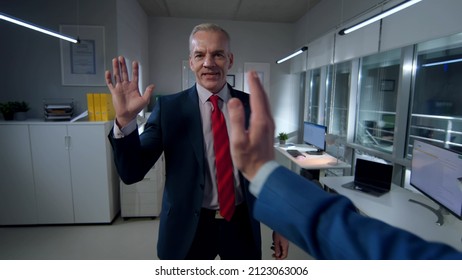 Pov shot of businessman giving high five to colleague in office. Happy entrepreneurs gesturing high-five working late.