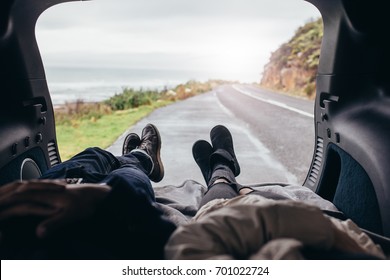 POV shot of couple lying in the car trunk. Man and woman relaxing in the car trunk along the road.
