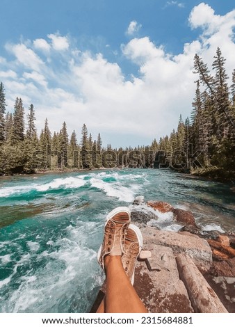 POV Shot. Crossed legs of a woman relaxing by the Kananaskis River in Canoe Meadows
