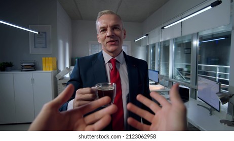 POV Shot Of Man Gesturing Hands And Talking To Colleague In Office. Businessmen Drink Coffee And Chat Working Late At Night