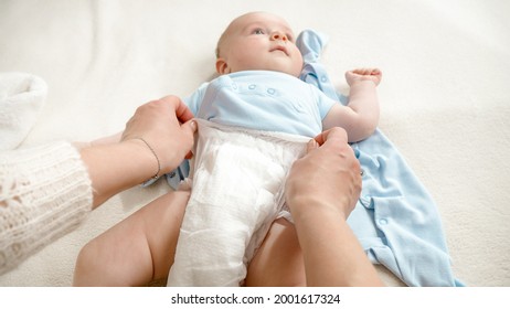 POV Shot Of Mother Changing Baby Diapers On Bed