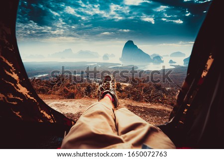 POV view of hipster tourist inside tent on front of mountains and sea. Adventure travel lifestyle wanderlust