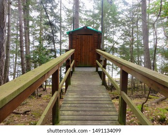 A PoV View Of Someone Walking Towards A Remote Wooden Outhouse In The Forest In The Gulf Islands Of British Columbia, Canada.