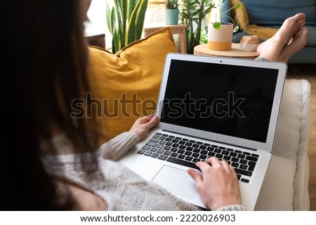POV of young caucasian woman using laptop relaxing at home lying on couch.