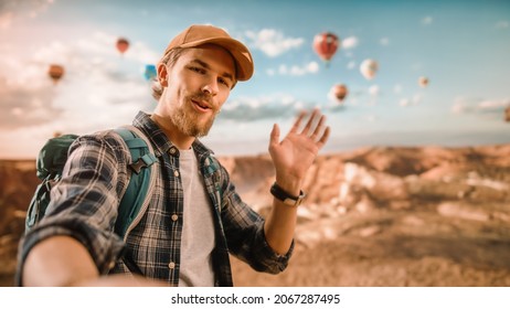 POV of Young Handsome Tourist Making Video Call or Record a Selfie Message on Social Media from Rocky Canyon Valley. Male Backpacker on Adventure Trip. Hot Air Balloons in Mountain National Park. - Powered by Shutterstock