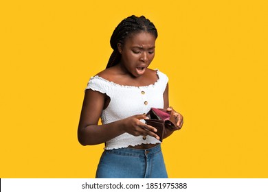 Poverty And Absence Of Money. Shocked African American Woman Checking Empty Wallet, Frustrated Black Lady Searching For Cash, Standing Isolated Over Yellow Studio Background, Copy Space