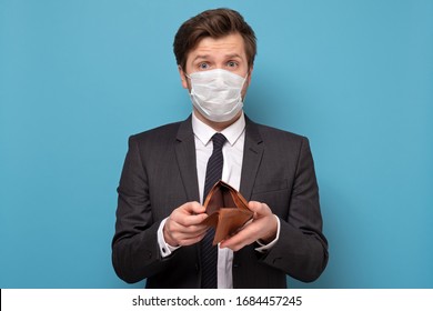 Poverty And Absence Of Money. Unemployed Sad Caucasian Man In Medical Mask And Suit Showing Empty Wallet, Blue Studio Background