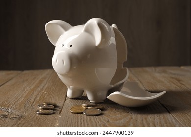 Poverty. Broken piggy bank and coins on wooden table - Powered by Shutterstock