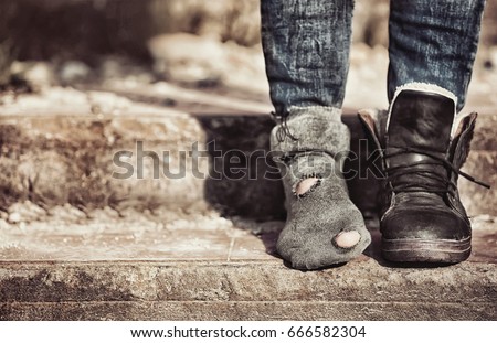 Poverty concept. Poor woman wearing tatter sock and one boot
