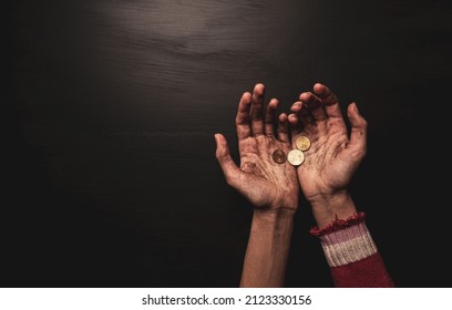 Poverty - kid begging for money. Dirty skinny beggar child’s hands with coins on black background. Layout with free copy (text) space. Captured from above (top view).