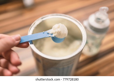 Powder Milk And Blue Spoon On Light Background Close-up. Milk Powder For Baby In Measuring Spoon On Can. Powdered Milk With Spoon For Baby. Baby Milk Formula And Baby Bottles. 