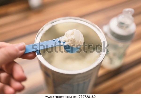 Powder milk and blue\
spoon on light background close-up. Milk powder for baby in\
measuring spoon on can. Powdered milk with spoon for baby. Baby\
Milk Formula and Baby Bottles.\
