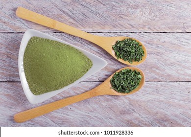 powder and moringa leaves in bowl on rustic wooden background