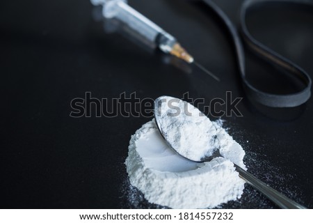 powder morphine on spoon and morphine in syringe with black rubber band on black wood background. Illegal drug. addictive substance, narcotic, habit-forming substance concept.