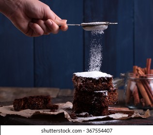 Powder Of Sugar Is Hung On A Pieces Of Christmas Chocolate Cake On Wooden Background. 