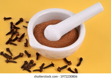 Powdered Clove Mortar With Pestle With Whole Cloves Close Up On Yellow Background