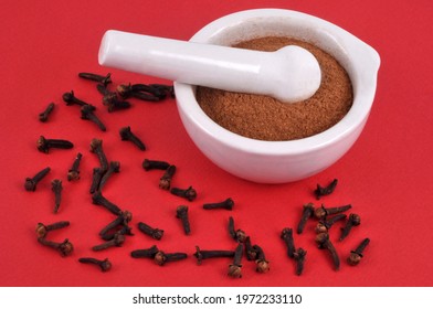 Powdered Clove Mortar With Pestle With Whole Cloves Close Up On Red Background