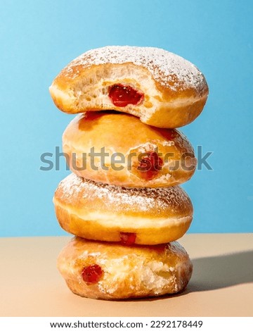 Powdered jelly donuts stacked on each other on a orange table with blue background 