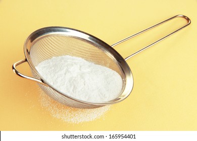 Powdered Sugar In Metal Sieve On Beige Background