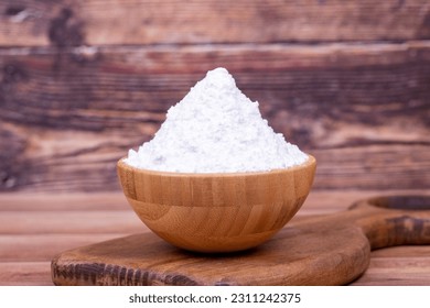 Powdered sugar on wooden background. Powdered or icing sugar in wood bowl