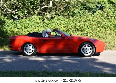 Powderham, Devon, Uk. July 9th 2022.  Porsche 944 Cabriolet Classic Car In Guards Red. Pictured Driving Down A Country Road On A Summers Day.