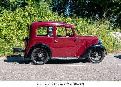 Powderham, Devon, Uk. July 9th 2022. Austin Seven Ruby Classic Car In Black And Dark Red, Cheeky Little Historic Vehicle With Wire Wheels. Pictured Driving Down A Country Road On A Summers Day.