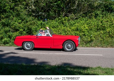 Powderham, Devon, Uk. July 9th 2022. MG Midget Classic Sports Car In Red. Fast And Nippy Rare Open Top Car With Wire Wheels. Pictured Driving Down A Country Road On A Summers Day. Car Rally.