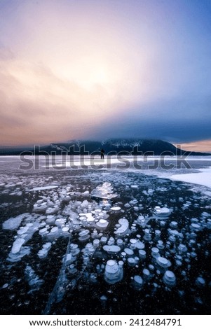 A powdery and moody sunrise at Abraham lake in Alberta Canada frozen in the Winter with the iconic Methane Bubbles in the foreground 