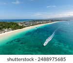 Powdery white sand beach with waves and boats running over the turquoise sea water. Boracay Island. Philippines.